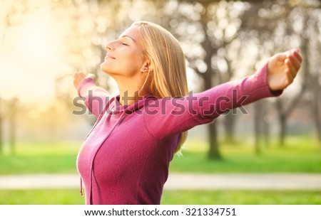 Young woman enjoying spring breeze in the park. The sun is shining.