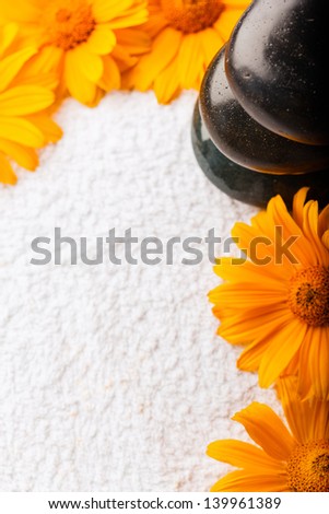 Spa stones on white towel with orange golden-daisy flower