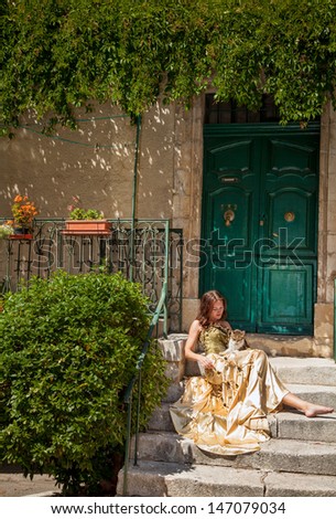 France. Life in Provence.Tiny town of Sault.Woman in a beautiful dress is sitting on the porch of the house and stroking a cat