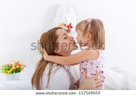 Mother and 4 years old daughter kissing in the bedroom
