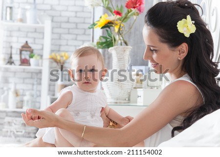 Good morning! Mother playing with a year-old daughter on the bed in the bedroom