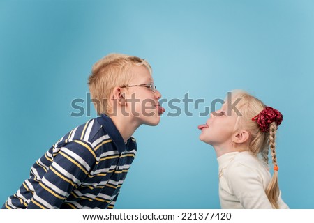 Teenage boy and girl stick out tongues to each other
