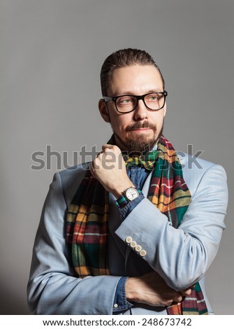 Fashionable handsome stylish bearded man with glasses and in a checkered scarf and bow tie.