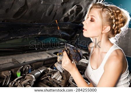 Girl checks the oil level with dipstick in their own broken car