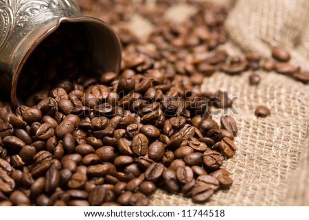 Cezve with freshly roasted coffee beans on sackcloth. Shallow depth of field. Focus on center of image