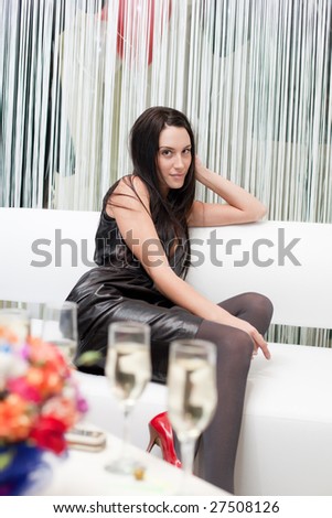Portrait of attractive fashion brunette woman sitting on white sofa on party