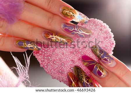 Human fingers with long acrylic fingernail and beautiful manicure holding pink heart