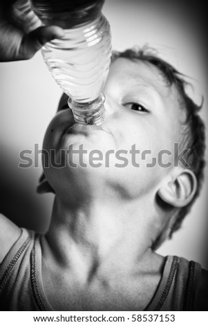 Quench thirst. The boy is drinking mineral water from plastic bottle. BW portrait with strong  vignetting.