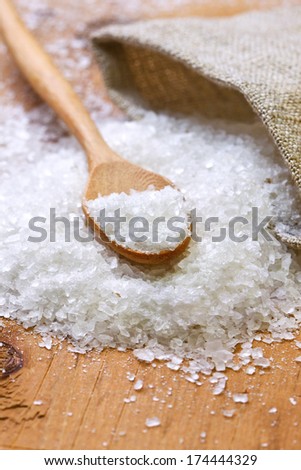salt and a wooden spoon, sacking on a wooden background