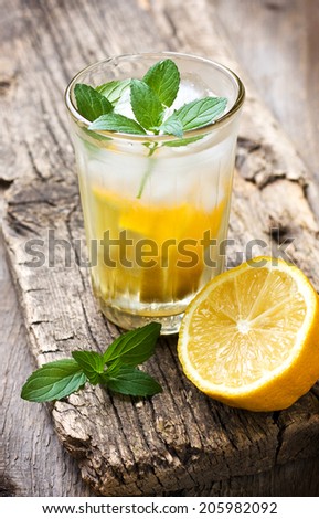 glass with lemonade and mint, lemon half on a wooden background