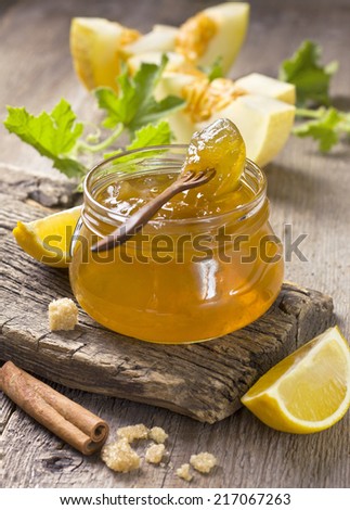 melon jam in a glass jar, the ingredients for preparation of jam on a wooden background