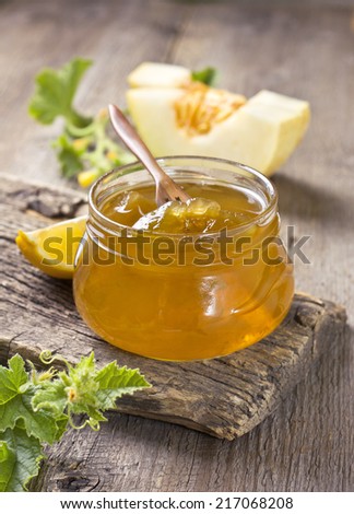 melon jam in a glass jar, the ingredients for preparation of jam on a wooden background