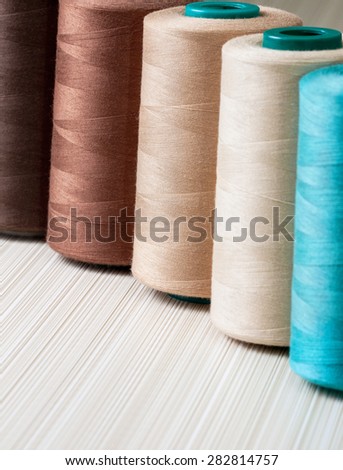 several spools of thread of beige and turquoise color