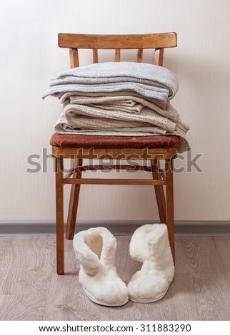 stack of warm clothes on the chair, Pair of warm winter sheepskin slippers