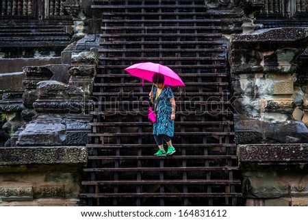 ANGKOR WAT, CAMBODIA - NOVEMBER 7, 2013: The rain does not stop a tourist from exploring one of the temples at Angkor Wat on November 7, 2013 just outside the town of Siem Reap, Cambodia.