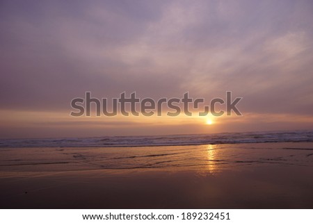 Golden sun setting on the Pacific Ocean  with surf and sea rocks,  near Yaquina Head, Newport, Oregon coast