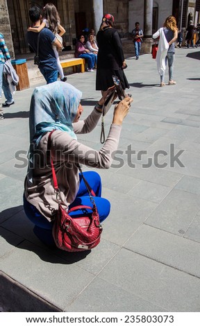 KONYA, TURKEY - JUN 2, 2014 - Young Turkish woman photographs friends  in the courtyard of the Mevlana Shrine,  Konya, Turkey