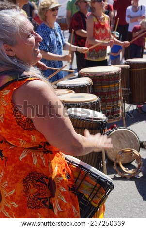 PENTICTON, BRITISH COLUMBIA - Jun 15 - Woman in bright colored dress plays the drum at the Saturday market on Jun 15, 2013 in Penticton, British Columbia, Canada..