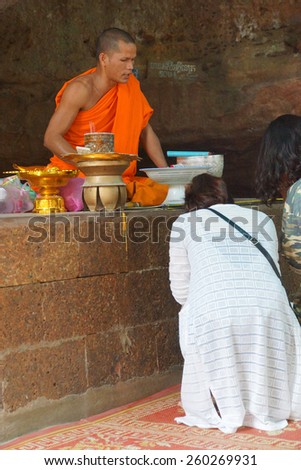 PHNOM KULEN, CAMBODIA - FEB 15, 2015 - Young Buddhist monk gives advice to visitors to the shrine at Phnom Kulen,  Cambodia