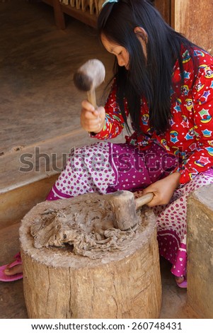 INLE LAKE, MYANMAR - FEB 28, 2015 - Young woman hammers mulberry pulp to make paper, near Inle Lake Myanmar (Burma)