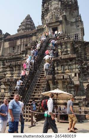 ANGKOR WAT, CAMBODIA - FEB 13, 2015 - Tourists climb the steep steps to the highest temple, Angkor Wat,  Cambodia
