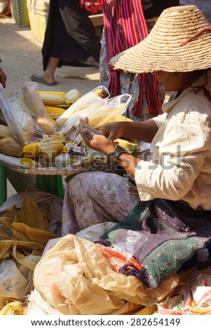 Young woman makes change while selling roasted corn on the cob,  Inle Lake,  Myanmar (Burma)
