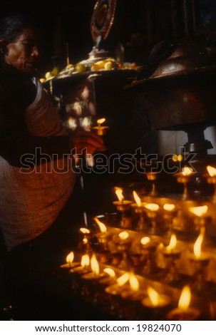 KATHMANDU NEPAL OCT 1979 - Nepali woman making offering at altar with candle lamps,	Swyambudnath Temple	Kathmandu	Nepal, Asia