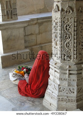 Woman in bright sari with intricately carved columns of   Jain temple, Ranakapur, India