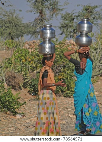 RAJASTHAN,  INDIA - DEC 2 -Young Indian women carry pots of water on their heads on  Dec 2, 2009 in Rajasthan, India.