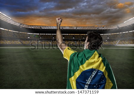 Brazilian soccer player with a Brazilian flag on his back, celebrating with the fans.