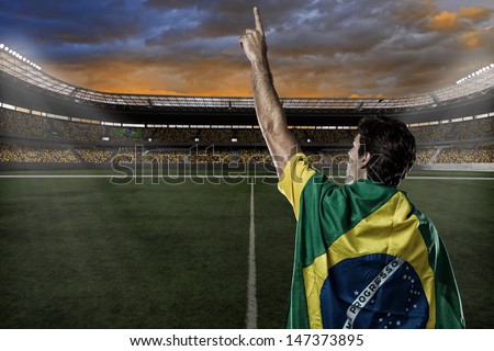 Brazilian soccer player with a Brazilian flag on his back, celebrating with the fans.