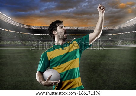 Rugby player in a green and gold uniform celebrating on a stadium.