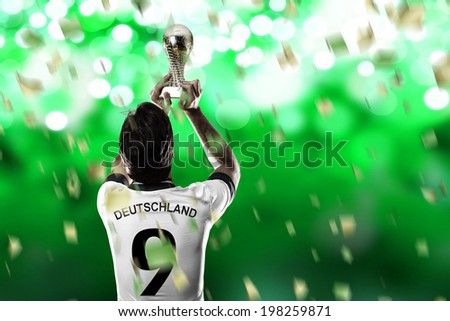 German soccer player, celebrating the championship with a trophy in his hand. On a green lights  background.