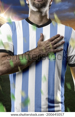 Argentinian soccer player, listening to the national anthem with his hand on his chest. On a stadium.