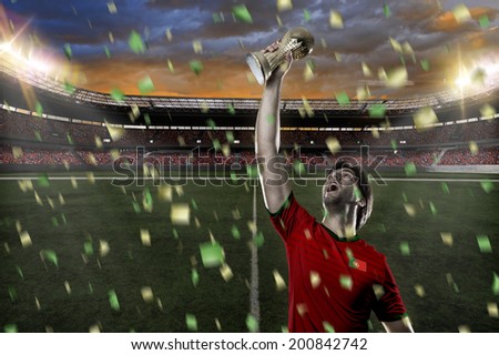 Portuguese soccer player, celebrating the championship with a trophy in his hand. On a stadium.