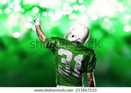 Football Player on a Green uniform celebrating on a Green lights background.