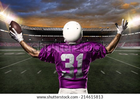 Football Player on a pink uniform celebrating on a stadium background.