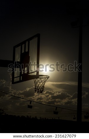 silhouette of a basketball hoop, under the sunset.