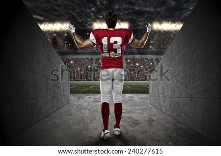 Football Player with a red uniform walking out of a Stadium tunnel.