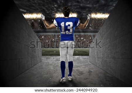 Football Player with a blue uniform walking out of a Stadium tunnel.