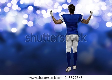 Football Player with a blue uniform walking, showing his back on a blue lights background.