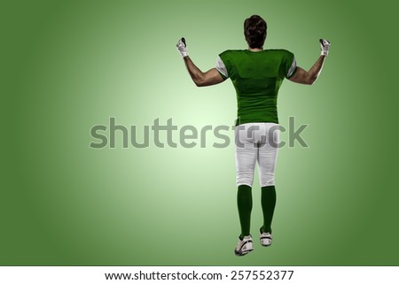 Football Player with a green uniform walking, showing his back on a green background.