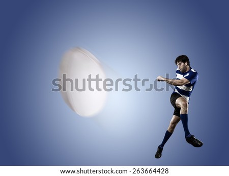 Rugby player in a blue uniform kicking a ball on a blue background.
