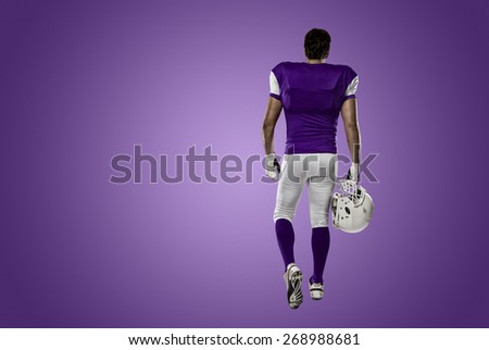 Football Player with a purple uniform walking, showing his back on a purple background.
