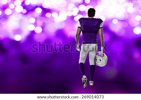 Football Player with a purple uniform walking, showing his back on a purple lights background.