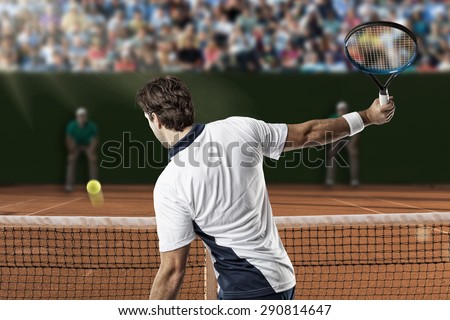 Tennis player returning a ball on a clay tennis court.