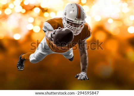 Football Player with a orange uniform scoring on a orange lights background.