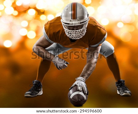Football Player with a orange uniform on the scrimmage line, on a orange lights background.