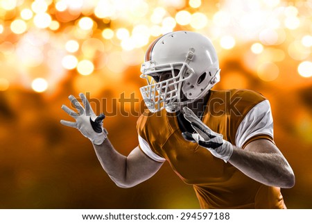 Football Player with a orange uniform making a tackle on a orange lights background.