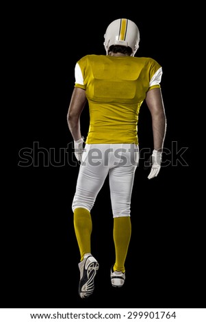 Football Player with a yellow uniform walking, showing his back on a black background.